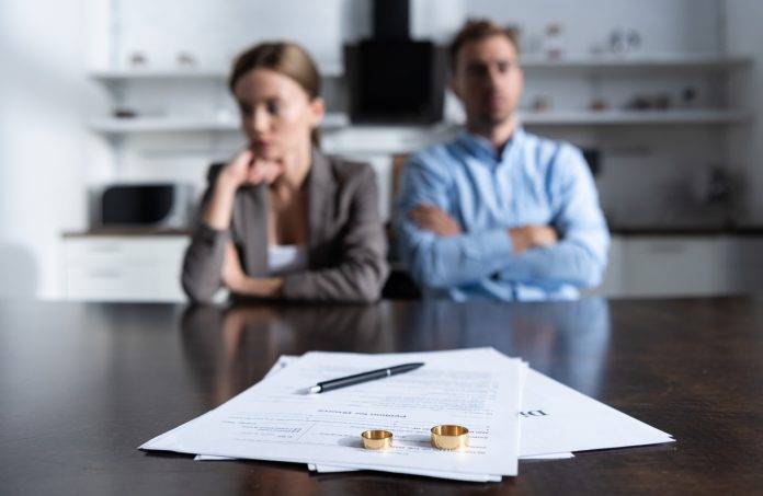 Люди, які готуються до розлучення. Офіційні документи на столі поруч з обручками.