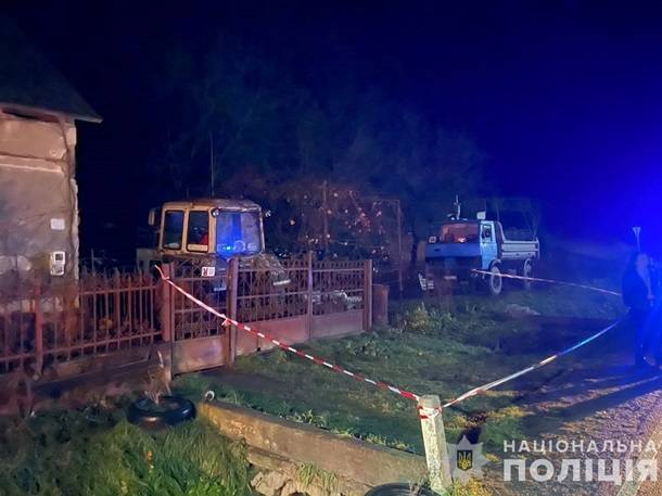 Будинок в який приїхала поліція у ночі на подвір'ї трактор стоїть