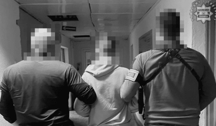 Два поліцейських ведуть підозрюваного по коридору